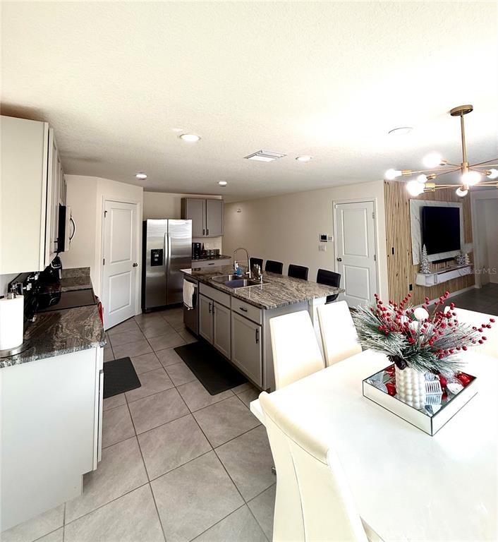 A kitchen with gray cabinetry, granite countertops, and an island, adjacent to a dining area — 3727 CAPRI COAST DRIVE, PLANT CITY, FL