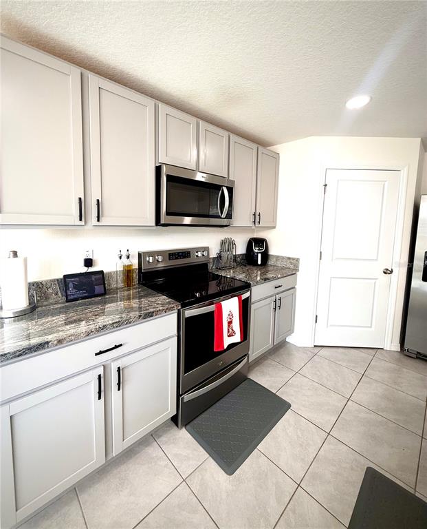 A kitchen features light gray cabinets, granite countertops, stainless steel appliances, and tile flooring — 3727 CAPRI COAST DRIVE, PLANT CITY, FL