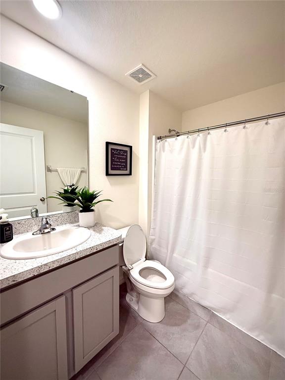 A bathroom features a vanity with a speckled countertop, a toilet, and a shower curtain — 3727 CAPRI COAST DRIVE, PLANT CITY, FL
