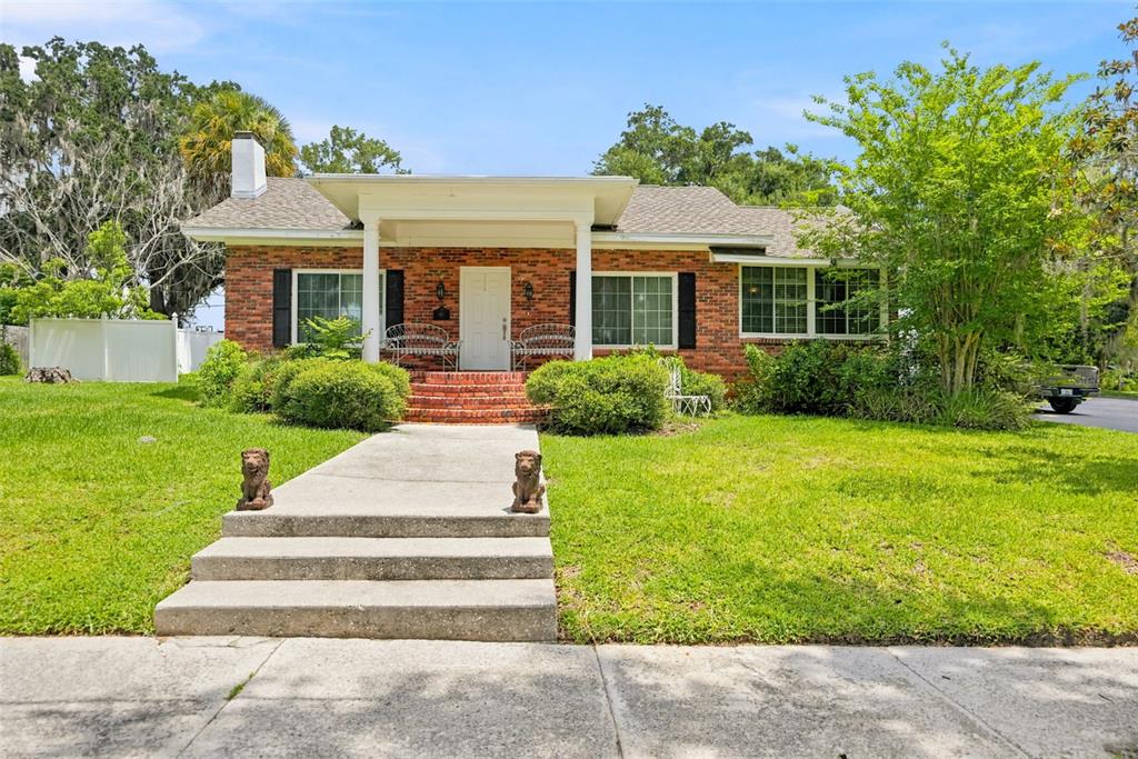 A single-story brick house with a front porch, concrete walkway, and two lion statues — 65 OLIVE STREET, BROOKSVILLE, FL