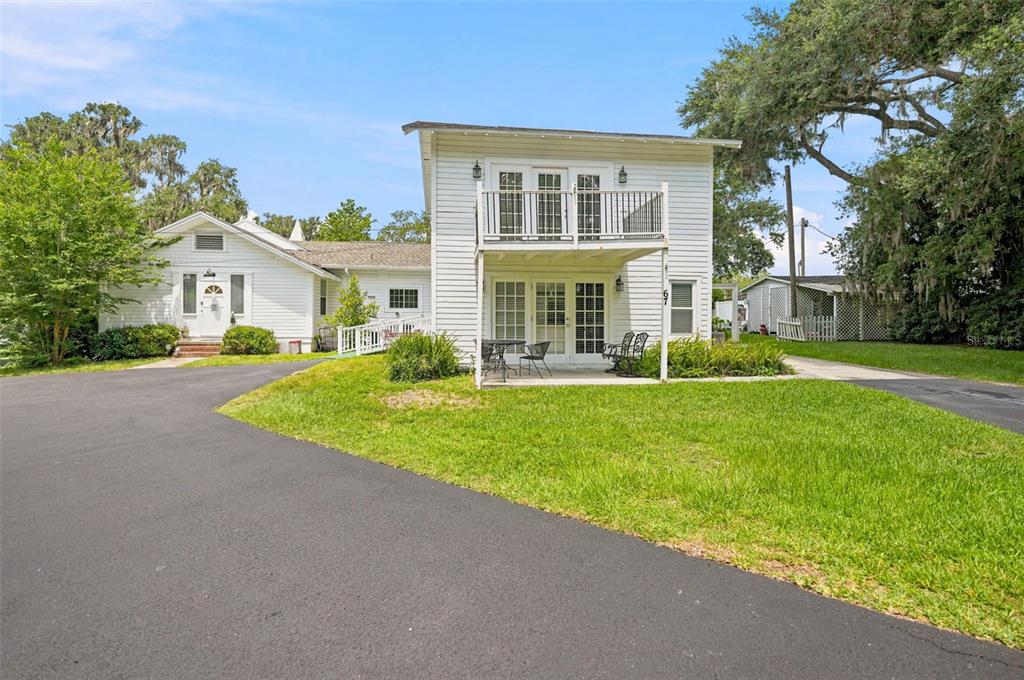 A two-story white house with a balcony and a paved driveway sits on a lawn — 65 OLIVE STREET, BROOKSVILLE, FL