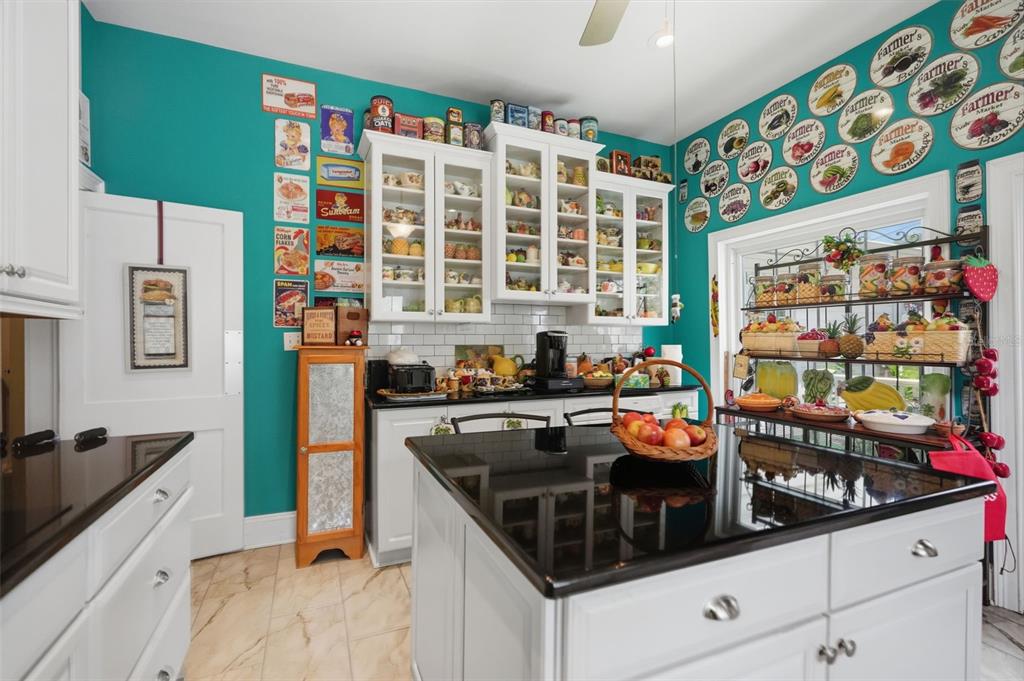 A kitchen with teal walls, white cabinets, a black island countertop, and decorative wall plates — 65 OLIVE STREET, BROOKSVILLE, FL