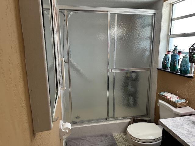 A bathroom features a glass sliding shower door, a white toilet, and a marble-patterned vanity — 611 S State Road 7 # 2e, Margate FL 33068, MARGATE, FL