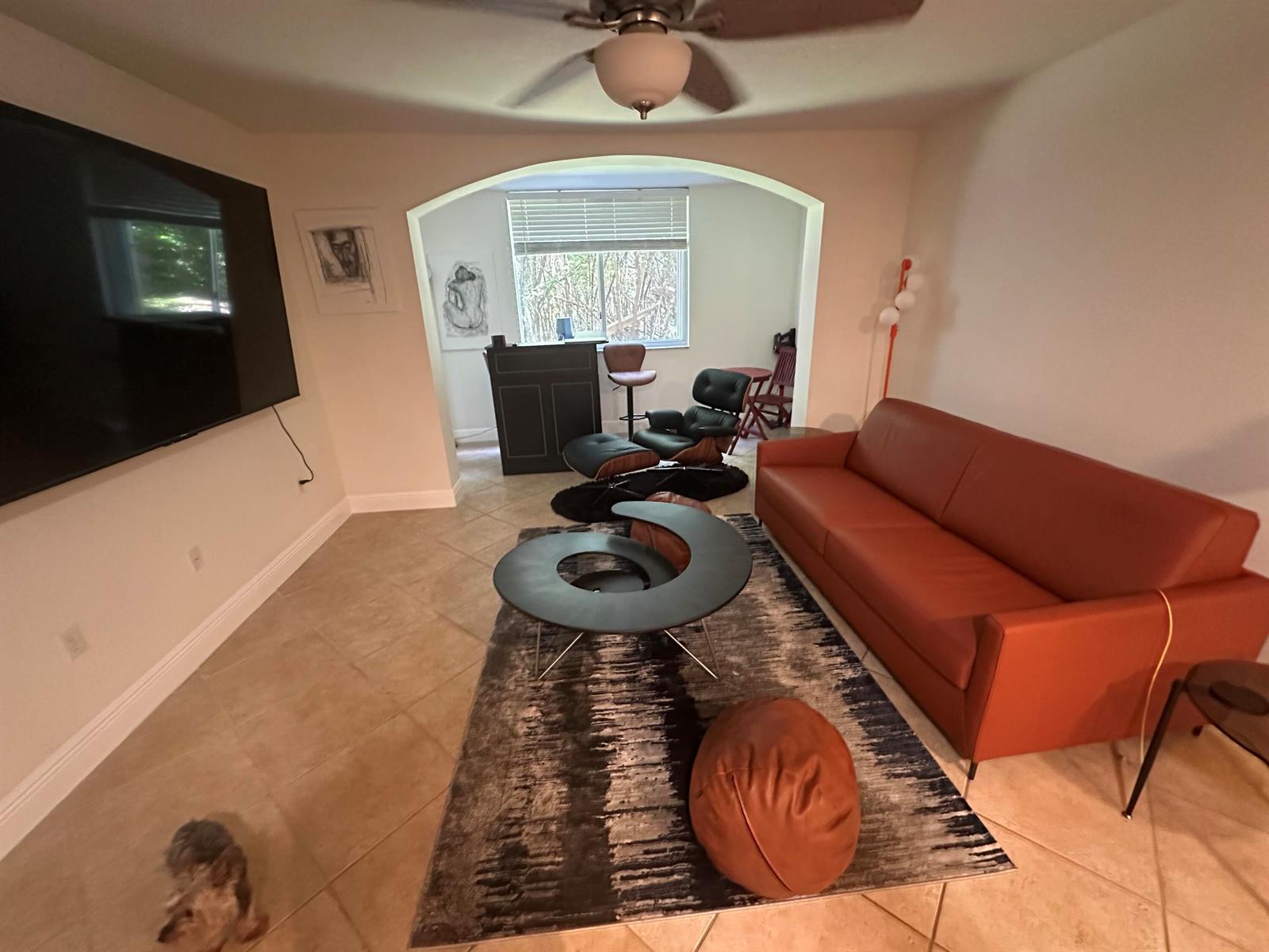 A living room features a rust-colored sofa, a unique coffee table, and an arched entryway — 400 Scotia Drive # 103, Hypoluxo FL 33462, HYPOLUXO, FL