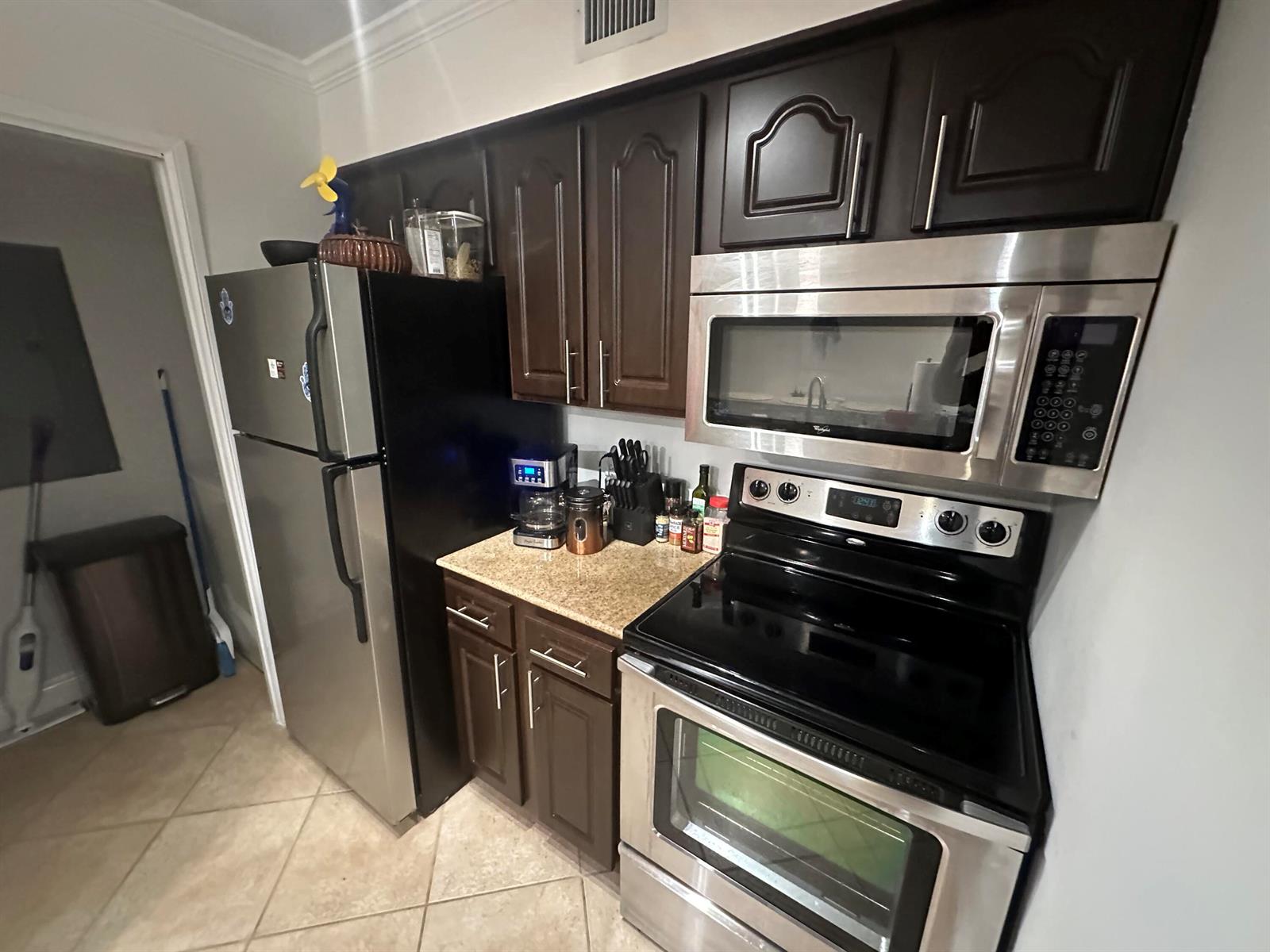 A kitchen features dark wood cabinets, stainless steel appliances, and granite countertops — 400 Scotia Drive # 103, Hypoluxo FL 33462, HYPOLUXO, FL