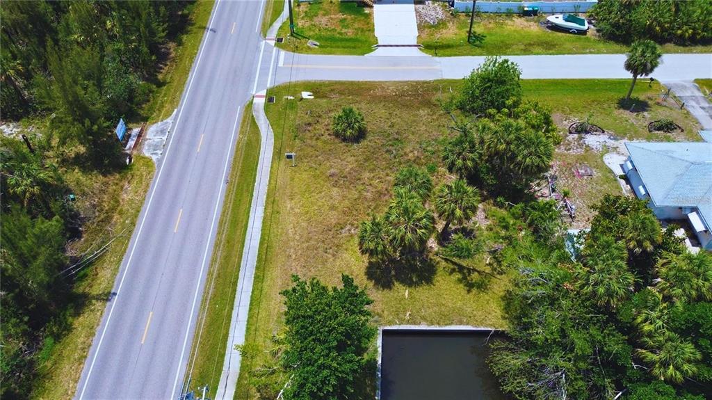 An aerial view shows a vacant, grassy corner lot with several palm trees and a pond — 3128 BANYAN WAY, PUNTA GORDA, FL