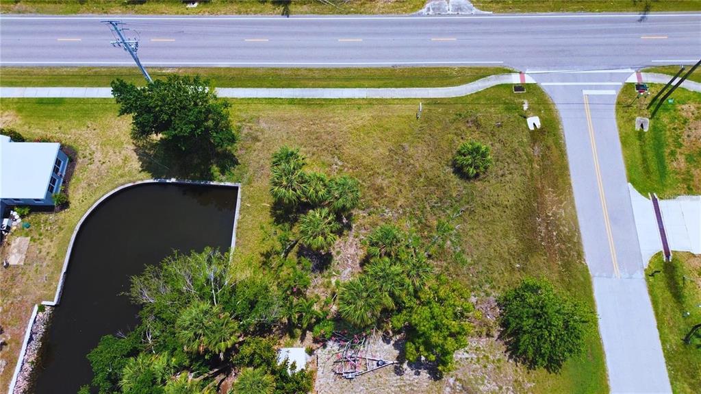 An aerial view shows a vacant, grassy lot with palm trees and a small pond — 3128 BANYAN WAY, PUNTA GORDA, FL
