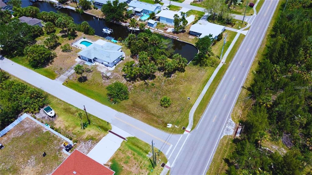 An aerial view shows a vacant residential lot situated between a road and a canal — 3128 BANYAN WAY, PUNTA GORDA, FL