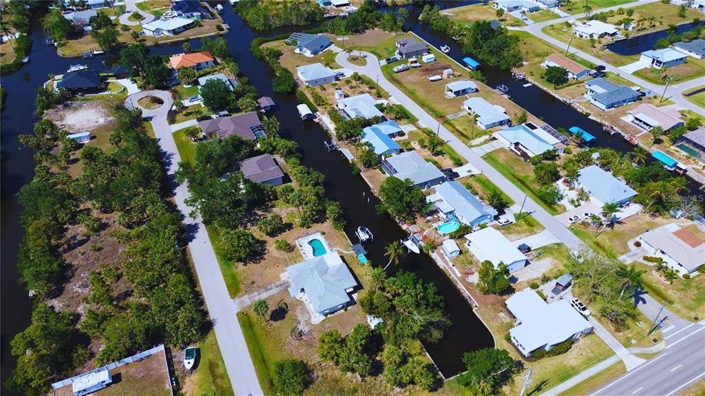 An aerial view shows residential houses along a canal in a suburban neighborhood — 3128 BANYAN WAY, PUNTA GORDA, FL