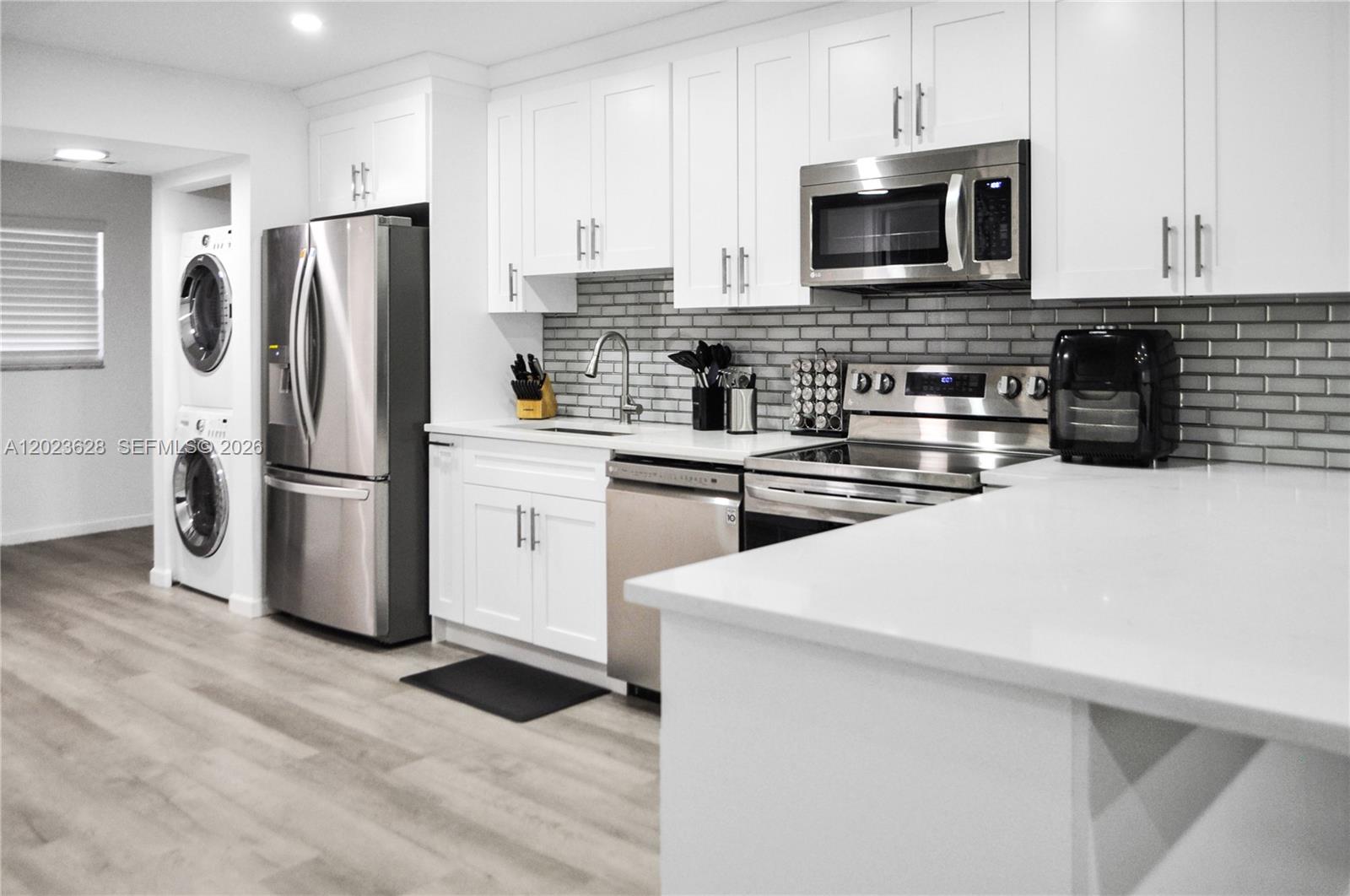 A modern kitchen features white cabinets, stainless steel appliances, and a gray subway tile backsplash — 1021 Mockingbird Ln # 202, Plantation FL 33324, PLANTATION, FL