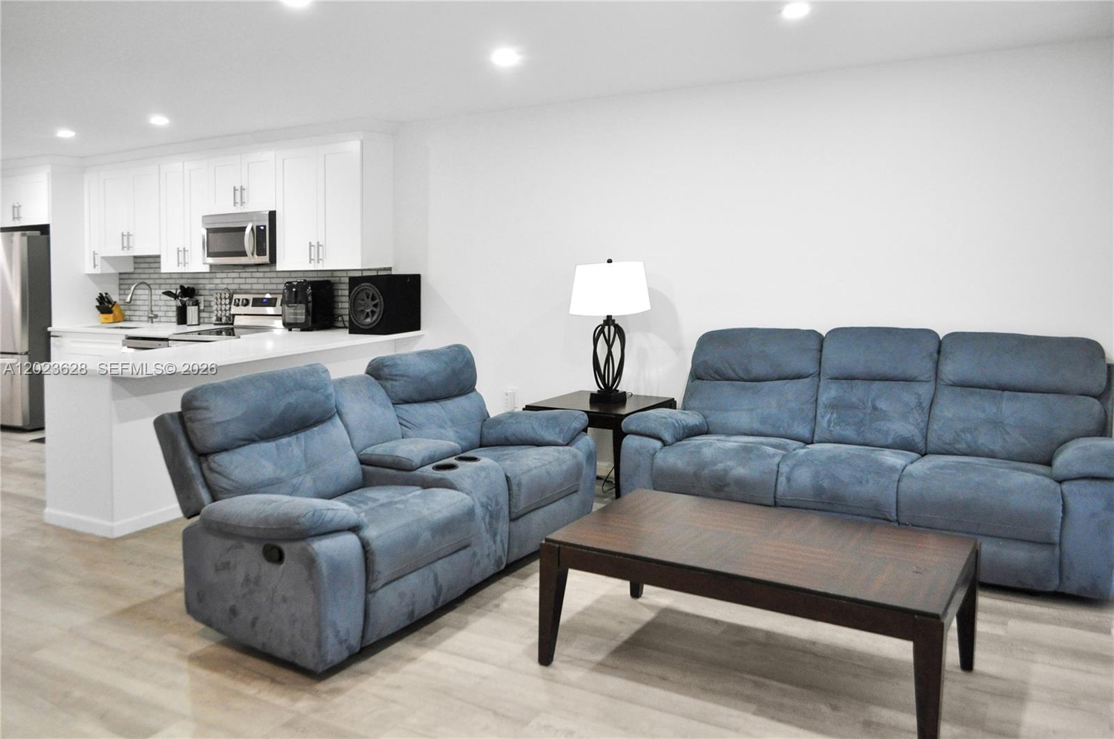 A living room with blue reclining sofas, a coffee table, and an open kitchen — 1021 Mockingbird Ln # 202, Plantation FL 33324, PLANTATION, FL