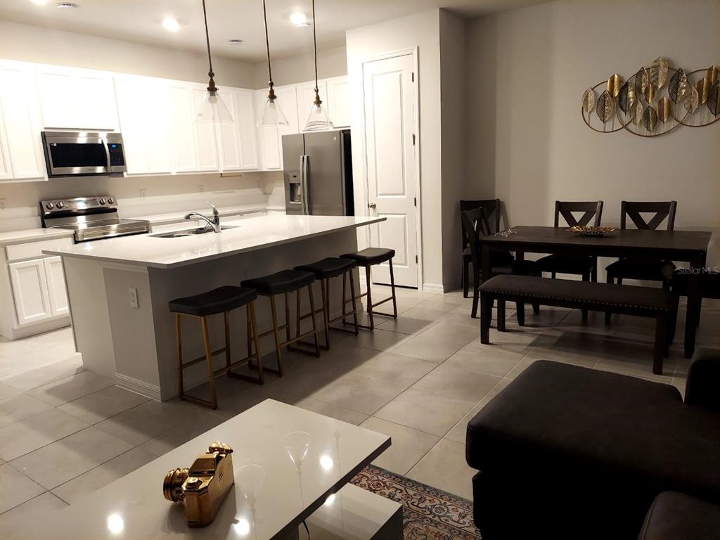 A kitchen with white cabinets, a quartz island with bar stools, and an adjacent dining area — 804 LONGBOAT DRIVE UNIT 804, DAVENPORT, FL