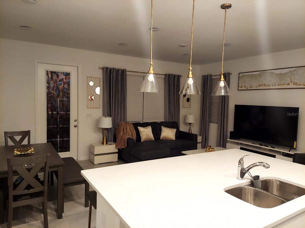 A kitchen island with a double sink overlooks a living room with a dark sofa — 804 LONGBOAT DRIVE UNIT 804, DAVENPORT, FL