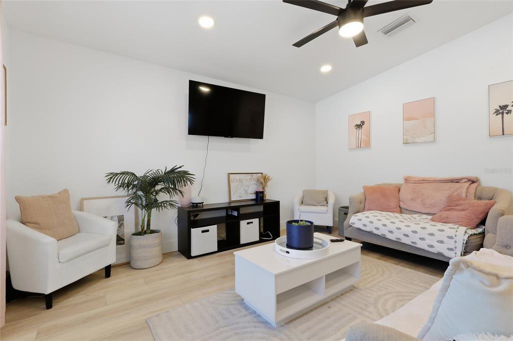 A living room features a wall-mounted television, a white coffee table, and light wood flooring — 1918 W PINE STREET, TAMPA, FL