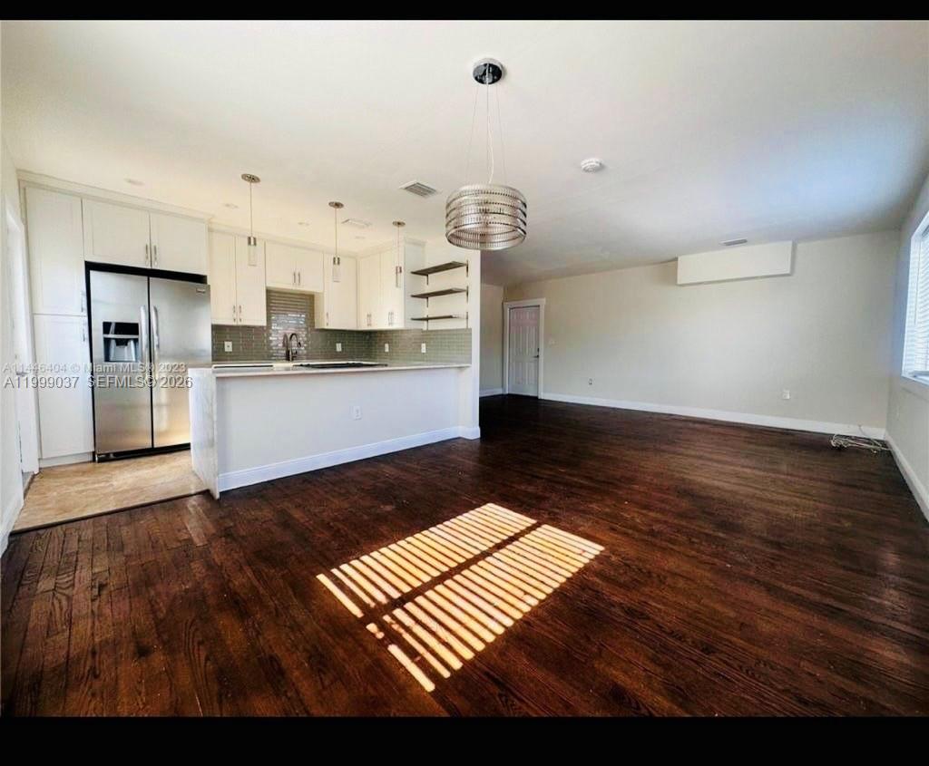 An open-concept kitchen with white cabinets and dark wood floors flows into a living area — 2775 SW 1st St, Miami FL 33135, MIAMI, FL