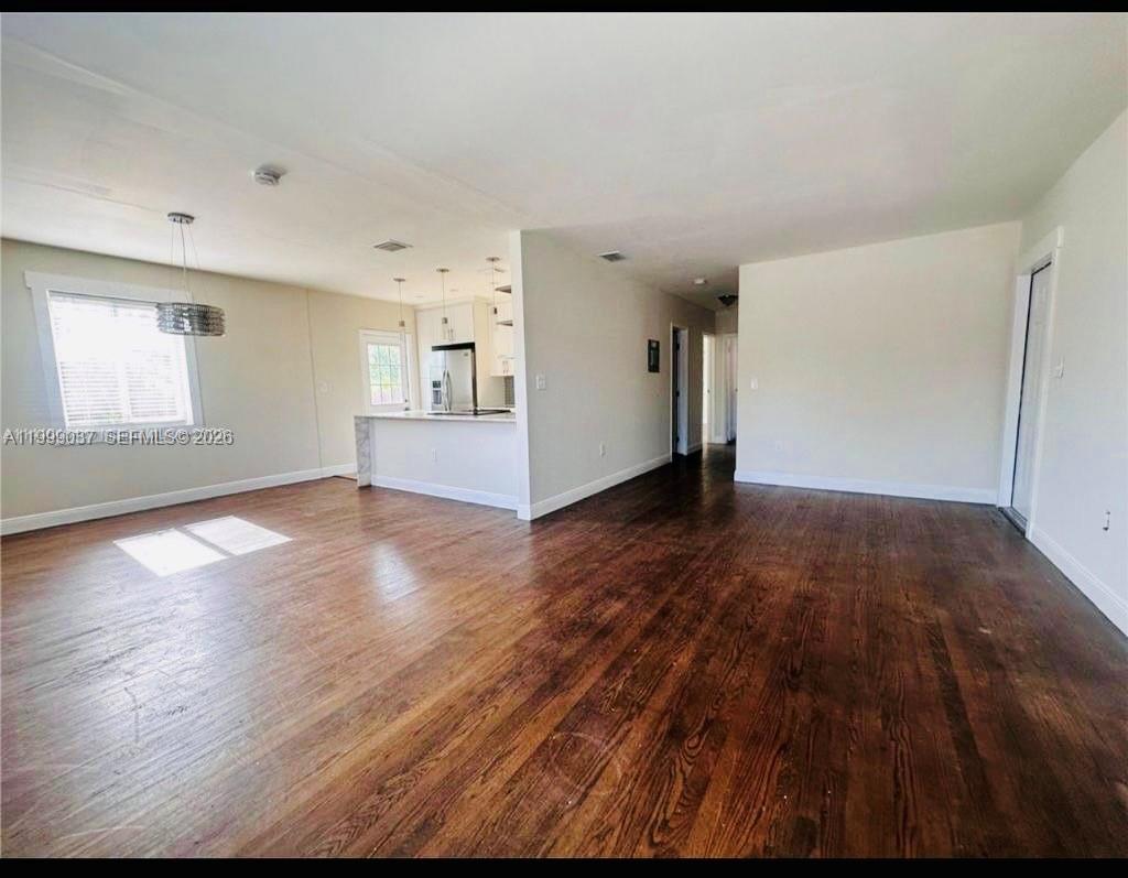 An open-concept living area with dark hardwood floors leads into a white kitchen — 2775 SW 1st St, Miami FL 33135, MIAMI, FL