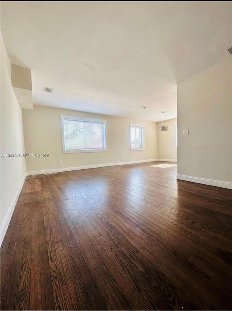 An empty room features dark hardwood floors, light-colored walls, and two windows — 2775 SW 1st St, Miami FL 33135, MIAMI, FL