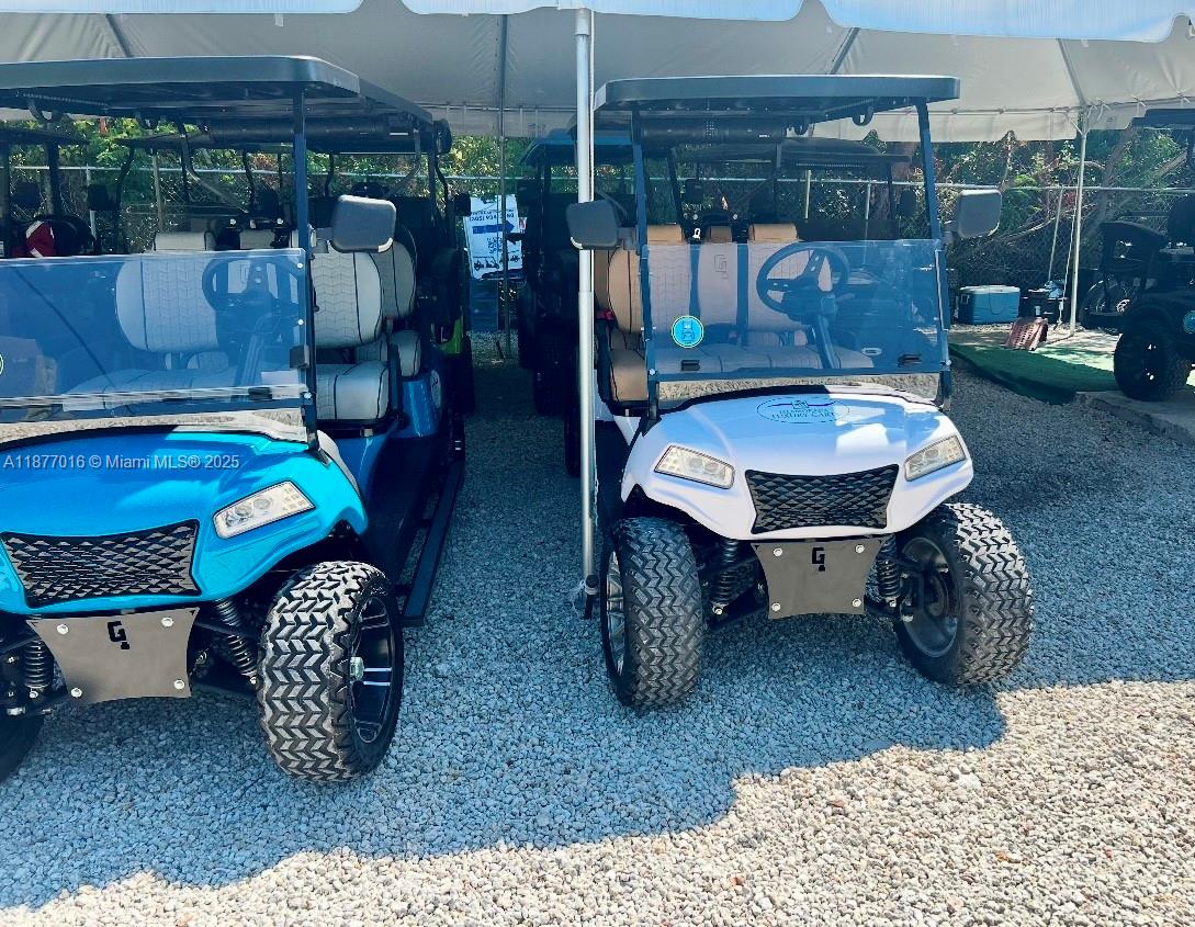Two golf carts are parked side-by-side under a white canopy on a gravel lot — 0000 Overseas Highway, Islamorada FL 33036, ISLAMORADA, FL