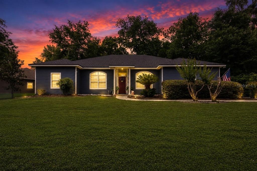 A blue single-story house with a dark roof stands behind a lawn at sunset — 5514 NW 78TH LANE, GAINESVILLE, FL