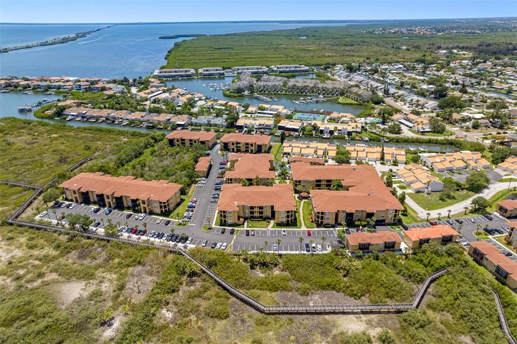 An aerial view shows multi-story apartment buildings surrounded by vegetation, parking lots, and a waterway — 4333 BAYSIDE VILLAGE DRIVE UNIT 102, TAMPA, FL