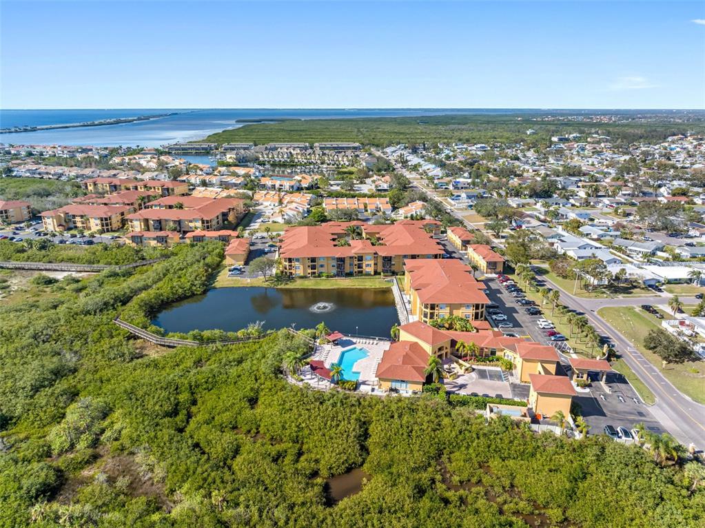 An aerial view shows a multi-story apartment complex with a pool and pond — 4333 BAYSIDE VILLAGE DRIVE UNIT 102, TAMPA, FL