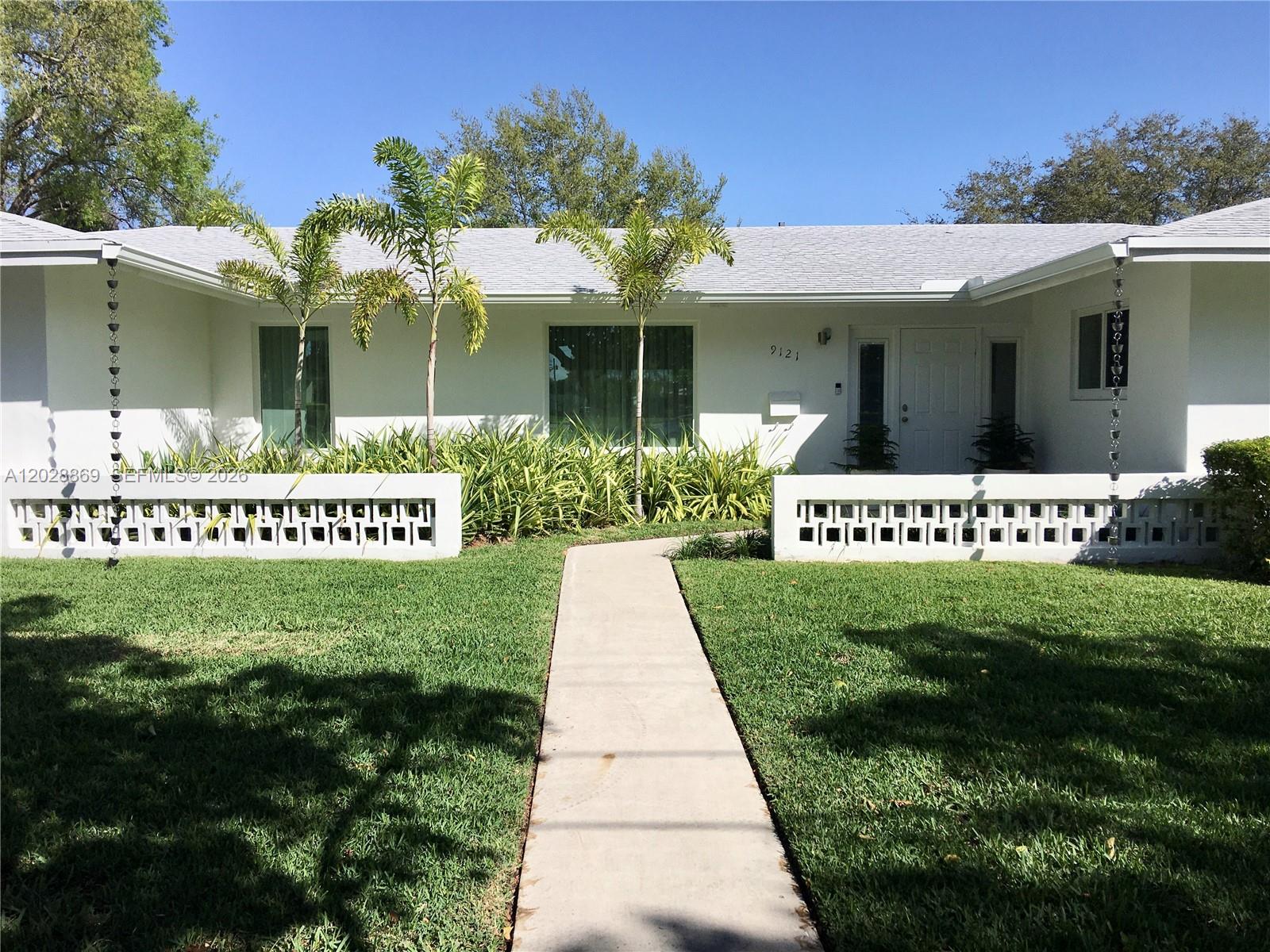 A white single-story house features a concrete walkway, decorative block walls, and two palm trees — 9121 SW 85th St, Miami FL 33173, MIAMI, FL