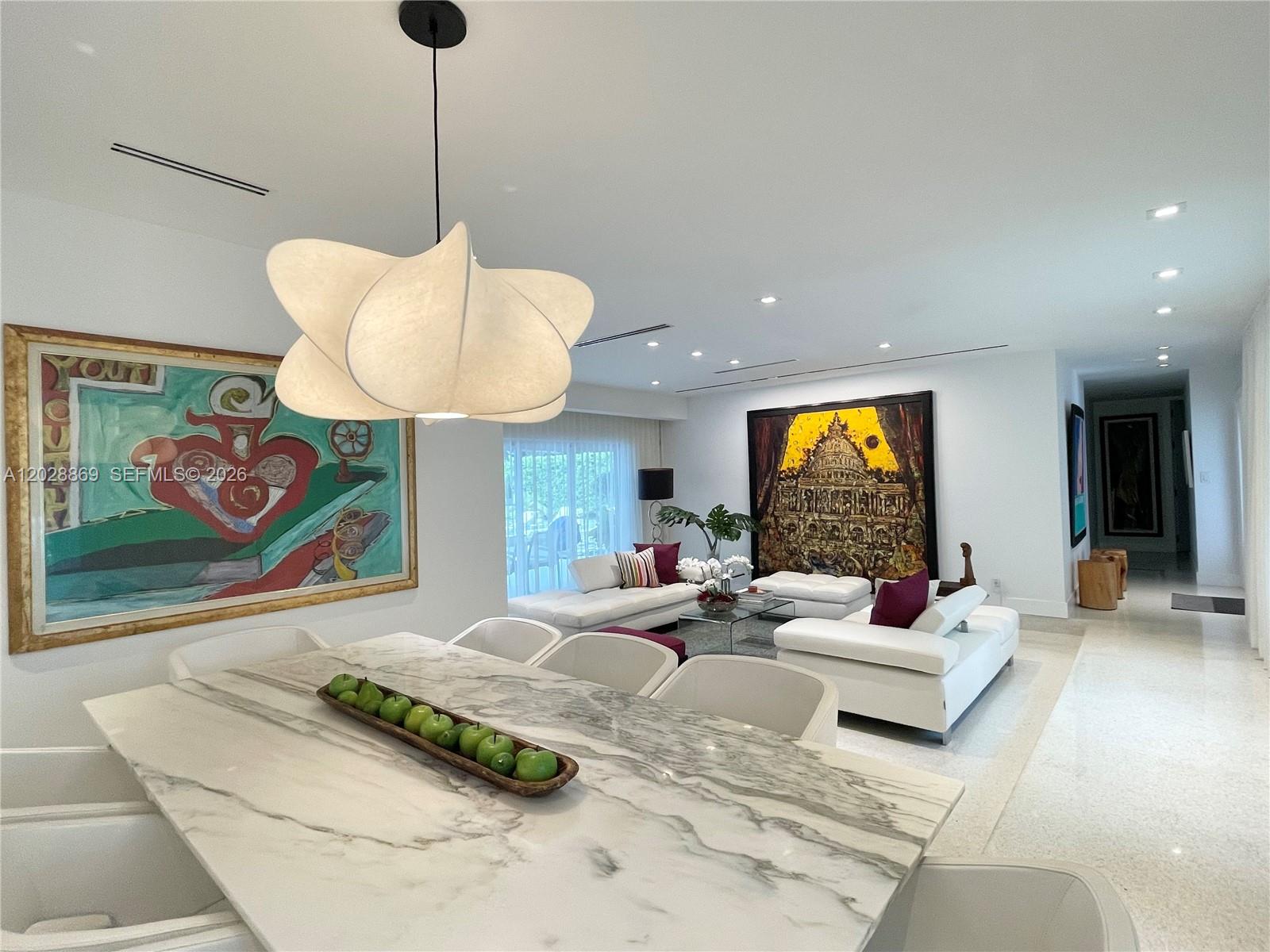A dining area with a marble table and pendant light overlooks a modern living room — 9121 SW 85th St, Miami FL 33173, MIAMI, FL