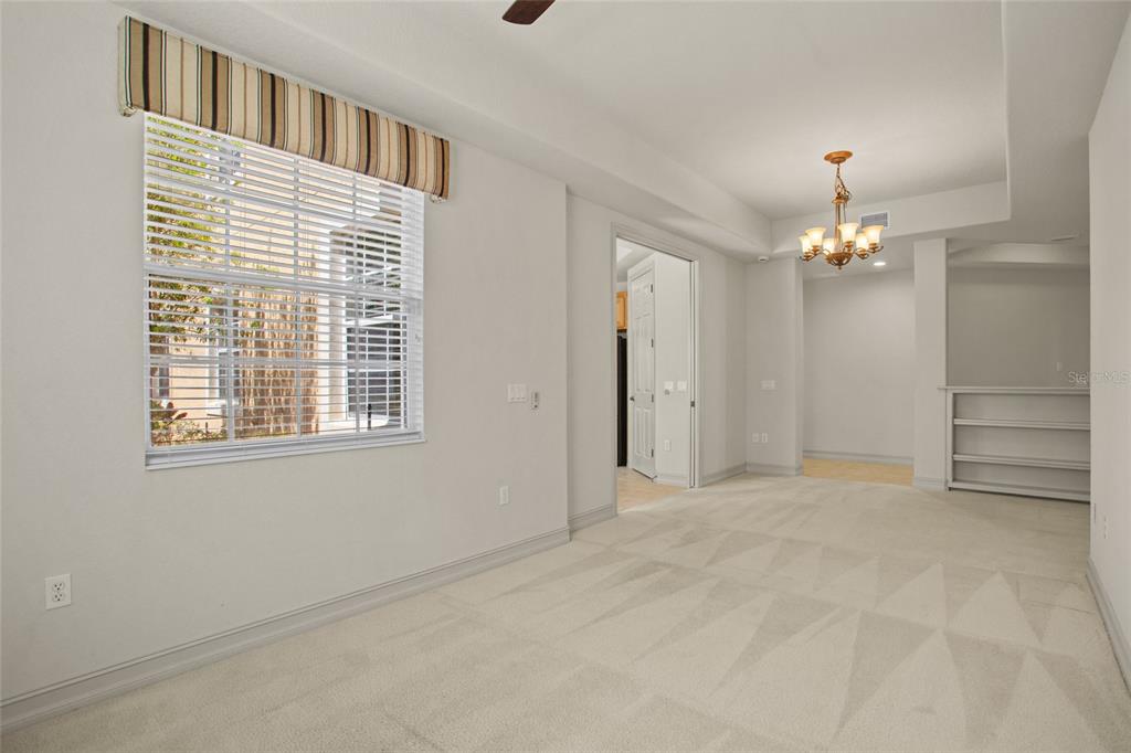 A carpeted room features a window with a striped valance, a chandelier, and an open doorway — 26207 AVENIDA LAS COLINAS, HOWEY IN THE HILLS, FL