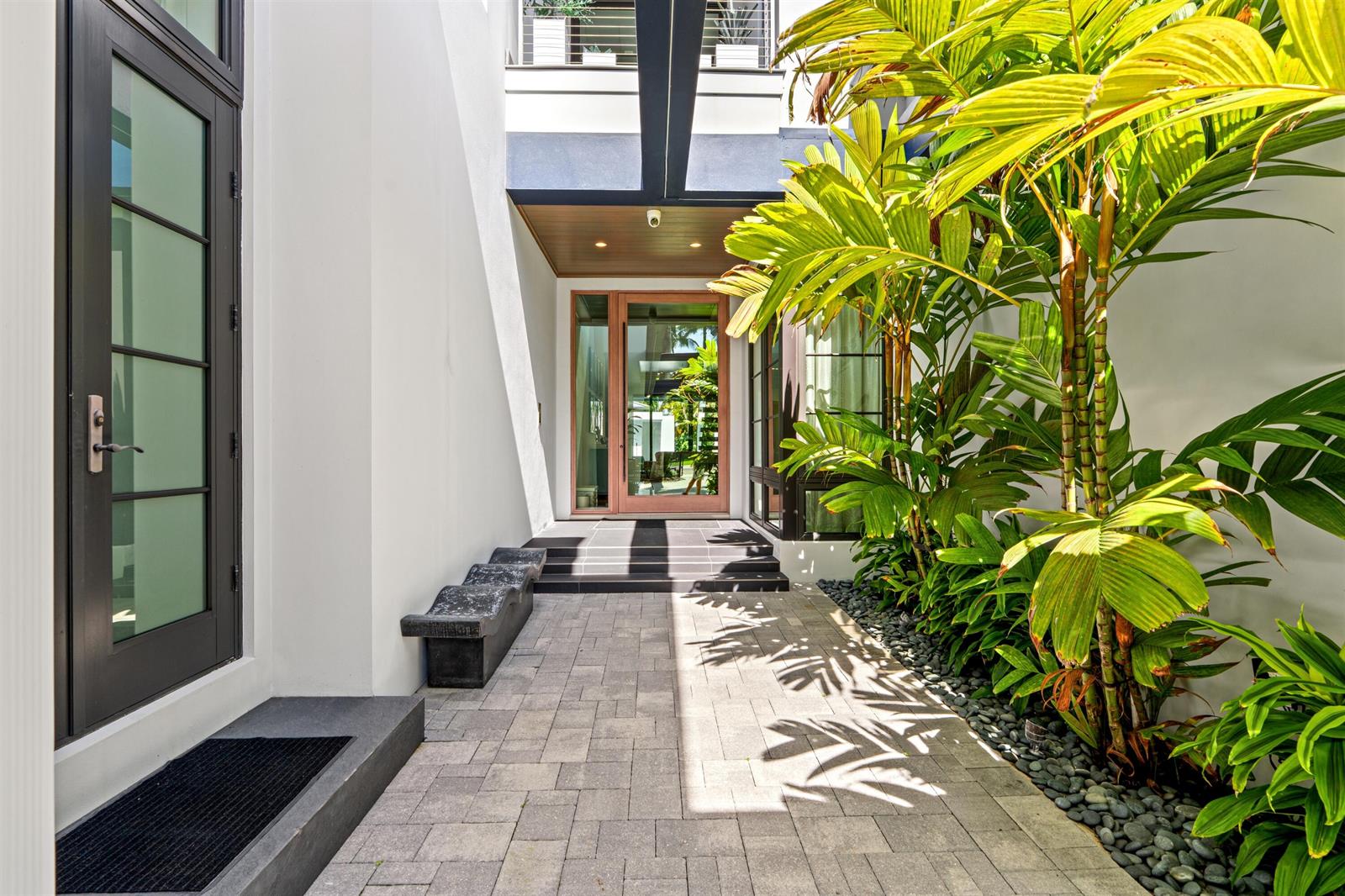 A paved walkway leads to a modern glass-paneled front door flanked by lush green palms — 1040 S Ocean Boulevard, Delray Beach FL 33483, DELRAY BEACH, FL