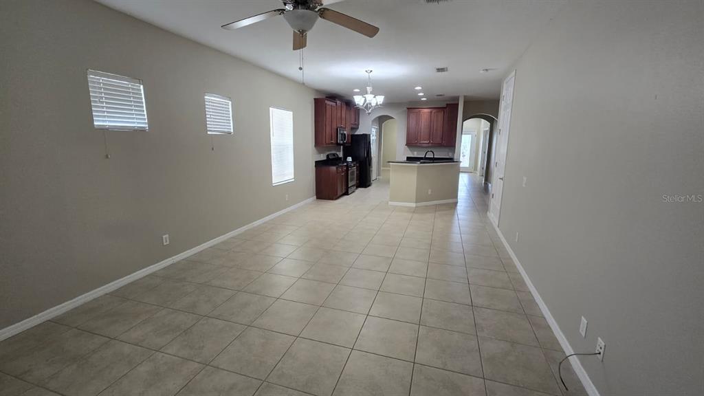 An open-concept kitchen and living area features tile flooring, dark wood cabinets, and neutral walls — 314 WINTERSIDE DRIVE, APOLLO BEACH, FL