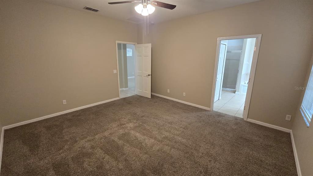 A carpeted bedroom features a ceiling fan, two doorways, and light-colored walls — 314 WINTERSIDE DRIVE, APOLLO BEACH, FL