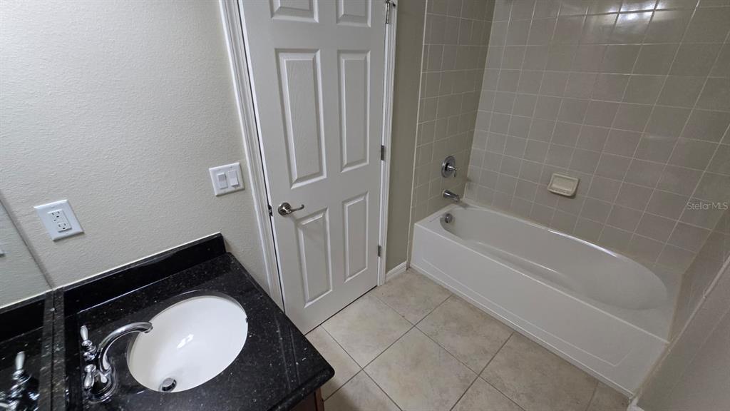 A bathroom features a vanity with a dark countertop and a tiled shower-tub combination — 314 WINTERSIDE DRIVE, APOLLO BEACH, FL