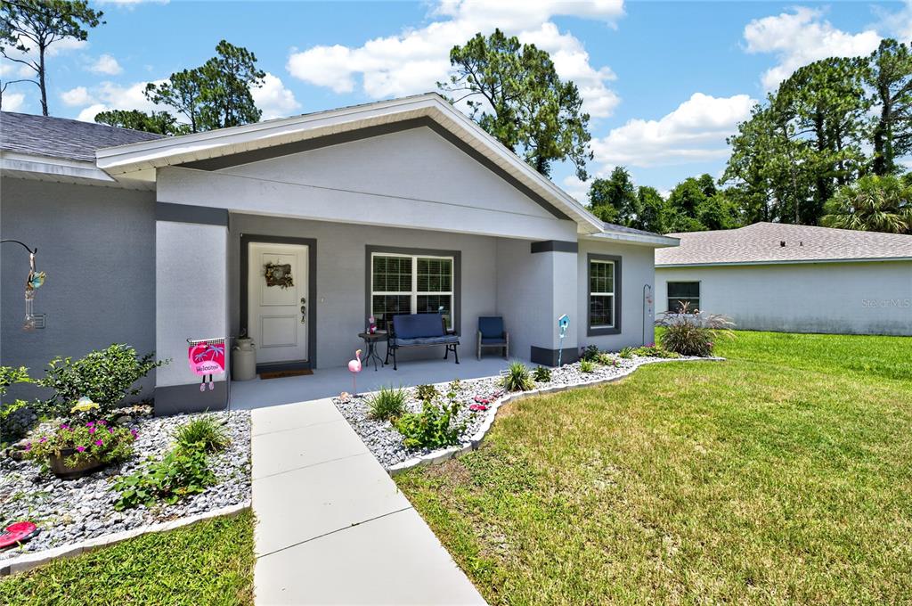 The exterior of a single-story house features a covered porch, a walkway, and landscaping — 70 PARKWAY DRIVE, PALM COAST, FL
