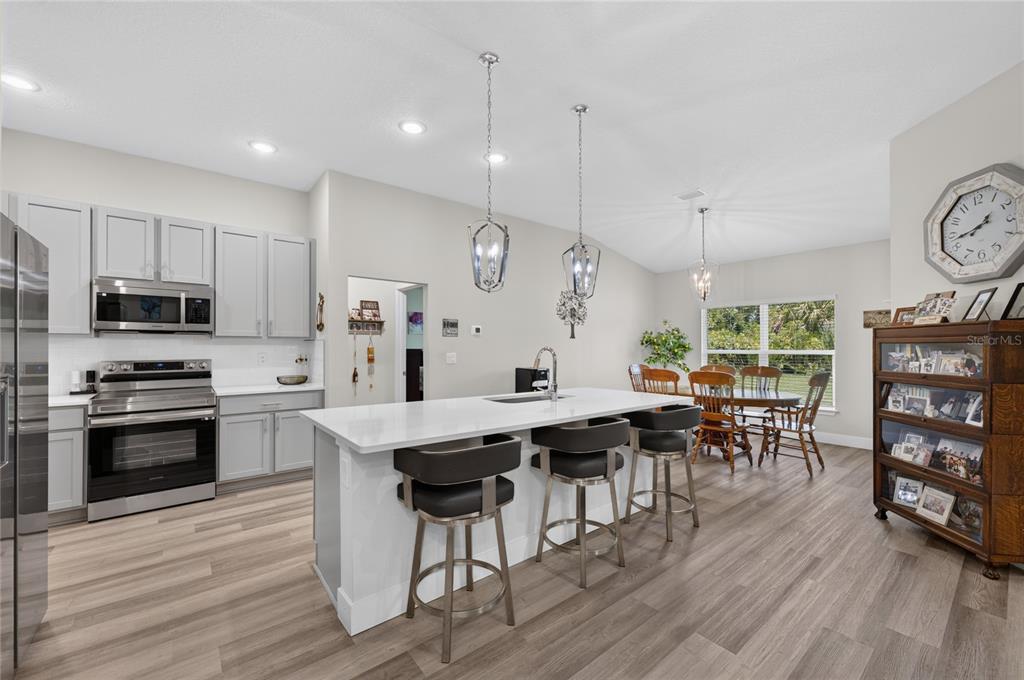 A kitchen with light gray cabinets, a white island with bar stools, and a dining area — 70 PARKWAY DRIVE, PALM COAST, FL