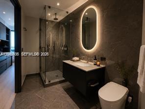 A modern bathroom features a glass-enclosed shower, a dark vanity, and an oval backlit mirror — 20 NE 11th ST # 3503B, Miami FL 33132, MIAMI, FL