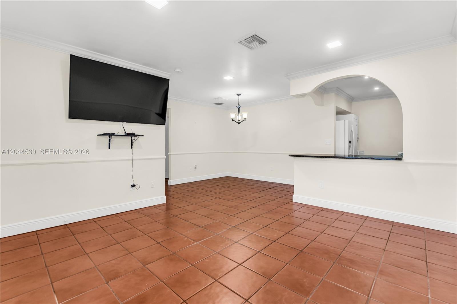 An open-concept living and dining area features terracotta tile flooring and a wall-mounted television — 15350 SW 72nd St # 24, Miami FL 33193, MIAMI, FL