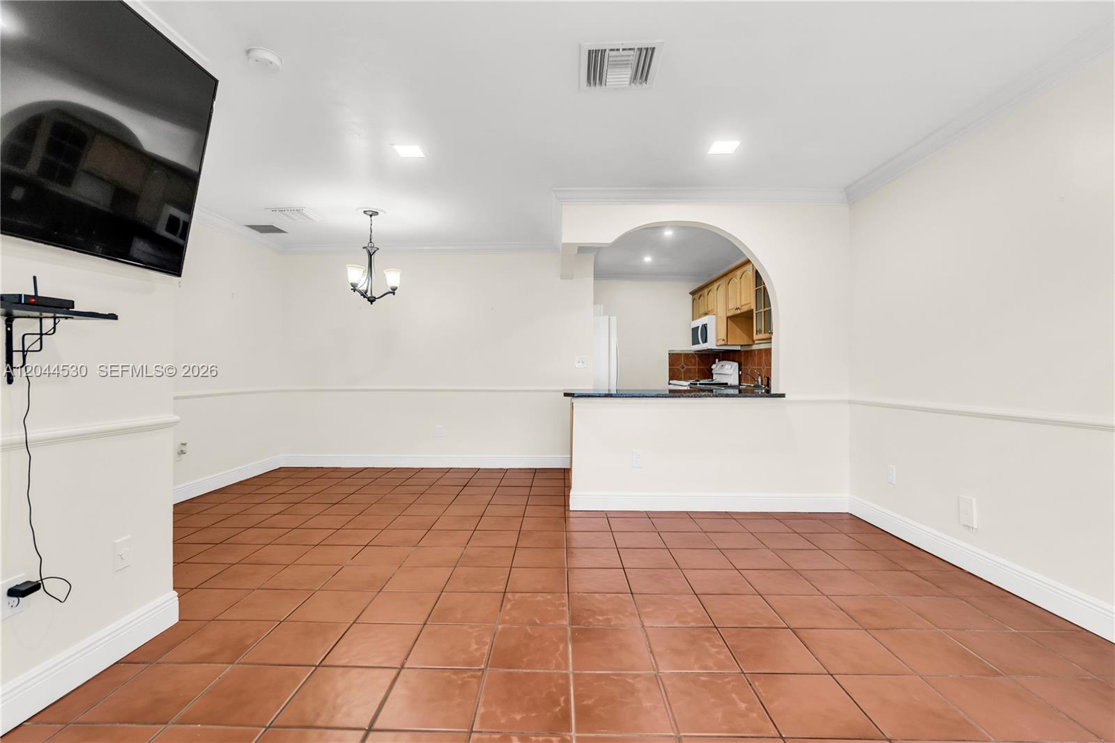 A dining area with terracotta tile floors features an arched opening into a kitchen — 15350 SW 72nd St # 24, Miami FL 33193, MIAMI, FL