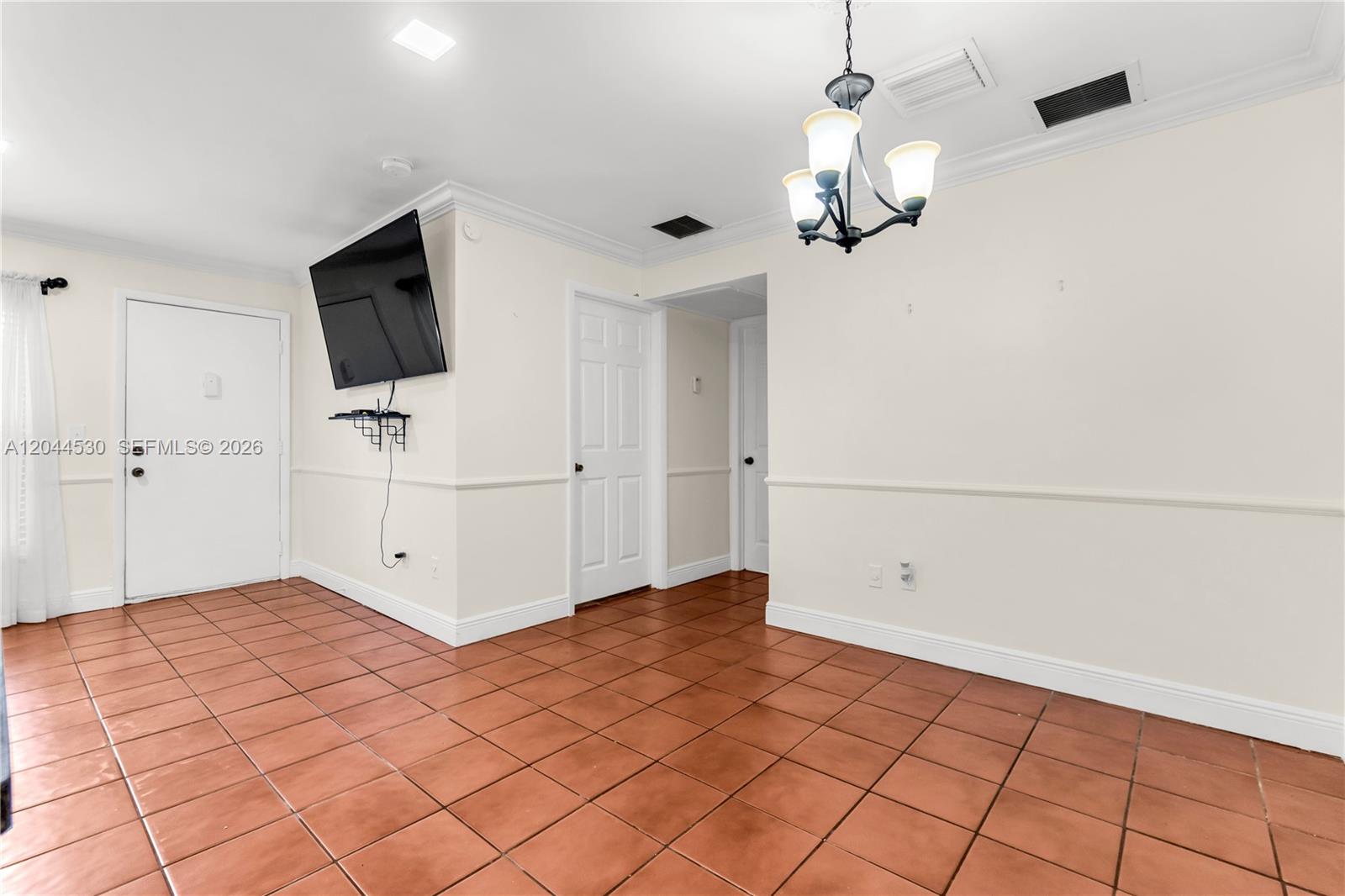 An interior room features terracotta tile flooring, a wall-mounted television, and a hanging chandelier — 15350 SW 72nd St # 24, Miami FL 33193, MIAMI, FL