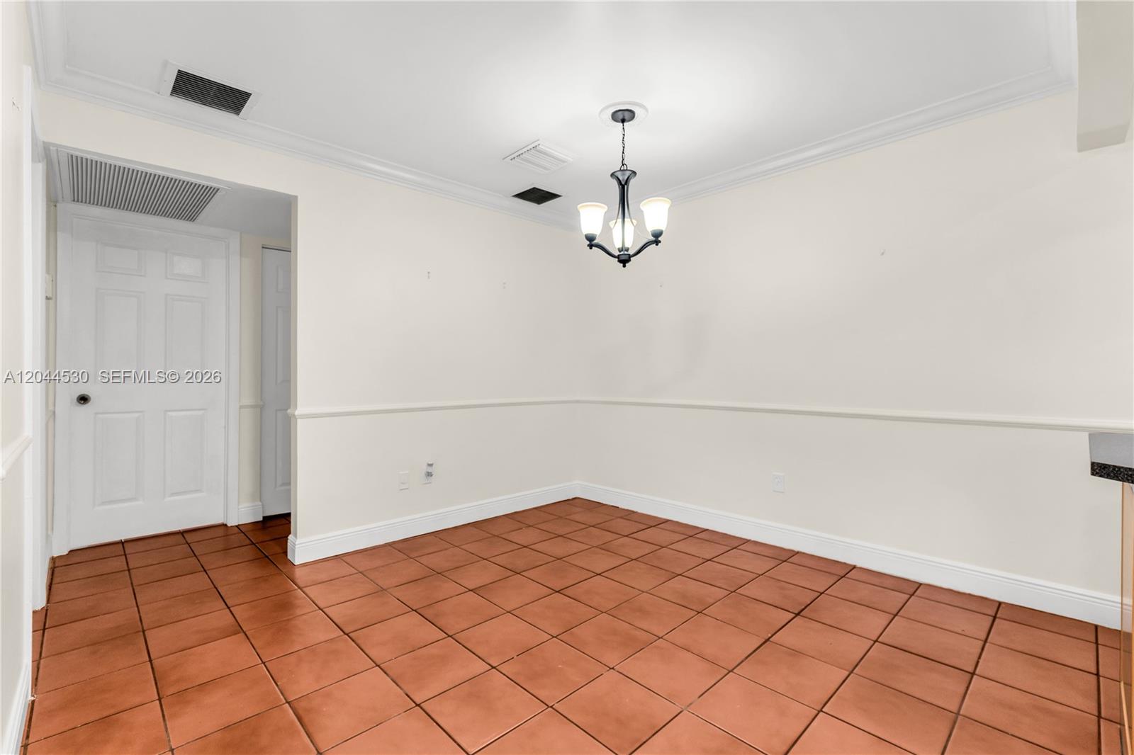 This dining area features terracotta tile flooring, white walls with chair rail molding, and a chandelier — 15350 SW 72nd St # 24, Miami FL 33193, MIAMI, FL