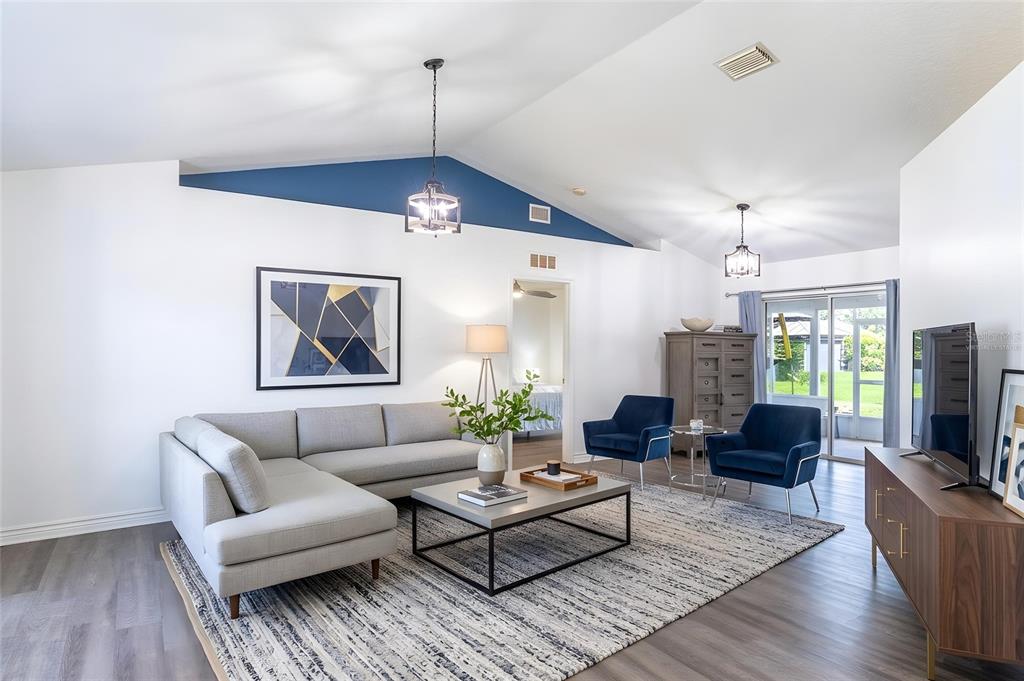 A living room features a gray sectional, blue armchairs, a coffee table, and vaulted ceilings — 2600 SHORTLEAF, KISSIMMEE, FL