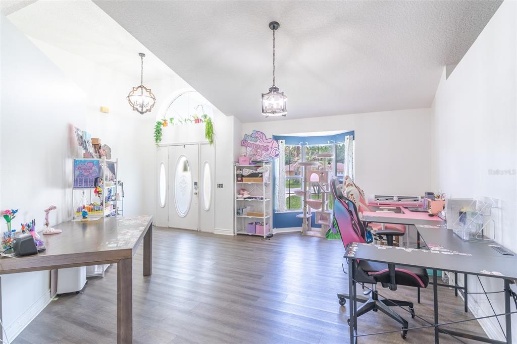 A bright room with wood-look flooring, two desks, a cat tree, and a front entryway — 2600 SHORTLEAF, KISSIMMEE, FL