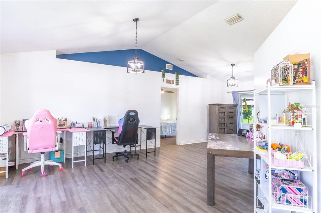 A room with wood-look flooring, a blue vaulted ceiling accent, two desks, and shelving — 2600 SHORTLEAF, KISSIMMEE, FL