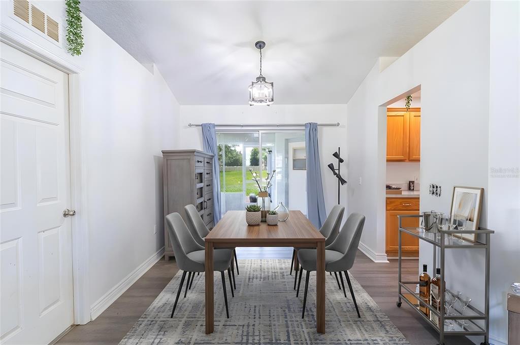 A dining room features a wooden table, six gray chairs, and a sliding glass door — 2600 SHORTLEAF, KISSIMMEE, FL