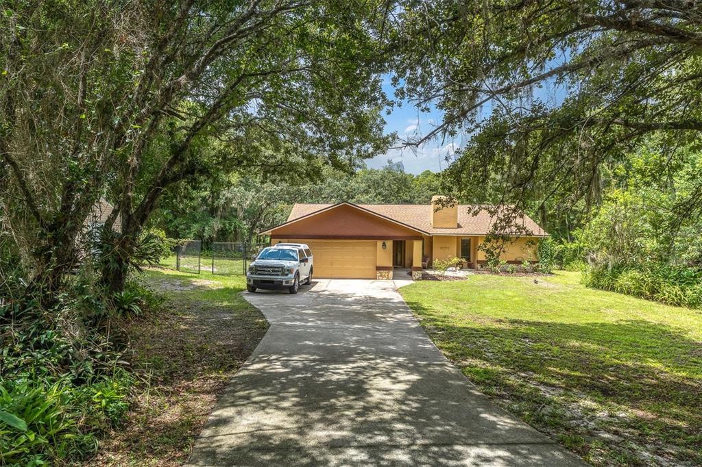A single-story house with a tan exterior, a two-car garage, and a concrete driveway — 6812 RIDGE TOP DRIVE, NEW PORT RICHEY, FL