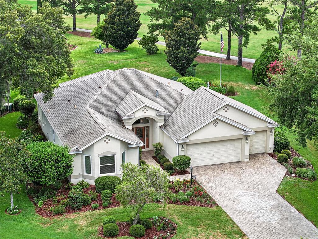 A single-story suburban house with a beige stucco exterior, a three-car garage, and landscaping — 16815 SE 85TH BELKNAP AVENUE, THE VILLAGES, FL