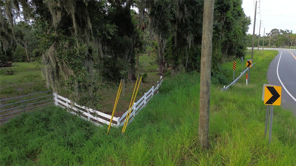 A white fence borders a grassy lot next to a road with traffic signs — 10900 OLD TAMPA ROAD, PARRISH, FL