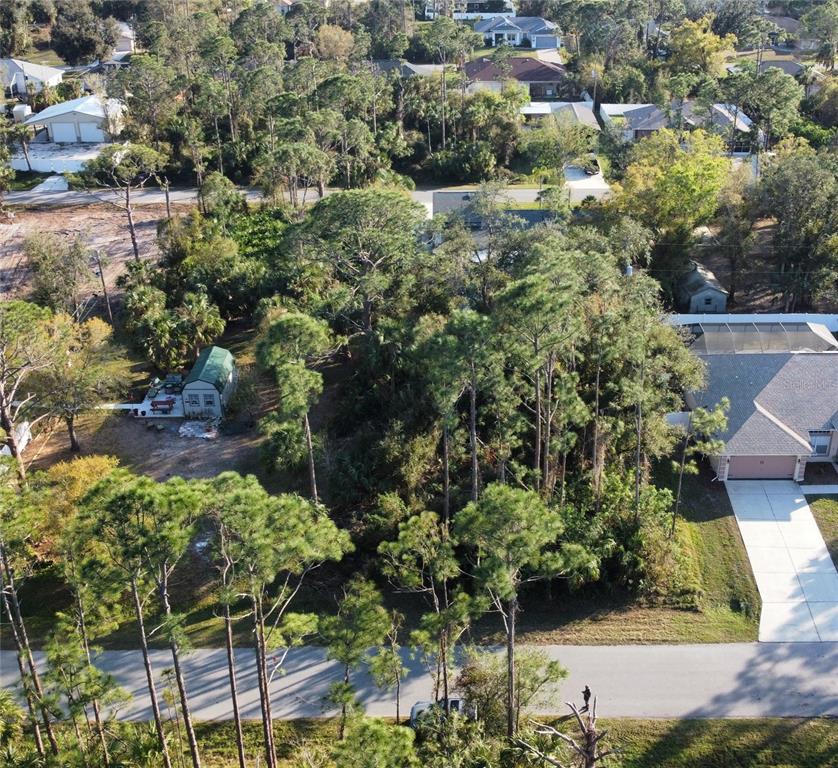 An aerial view shows a wooded residential lot situated between two houses and a street — SYLVANIA AVENUE, NORTH PORT, FL