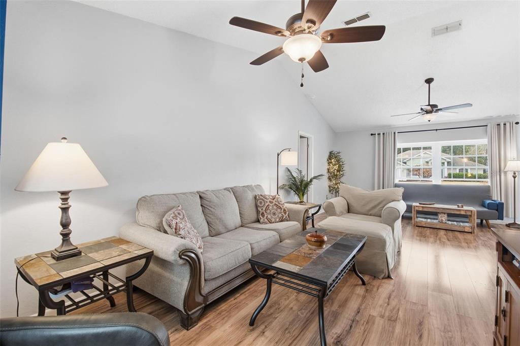 A living room features a vaulted ceiling, two ceiling fans, and wood-look flooring — 22 FORDHAM LANE, PALM COAST, FL