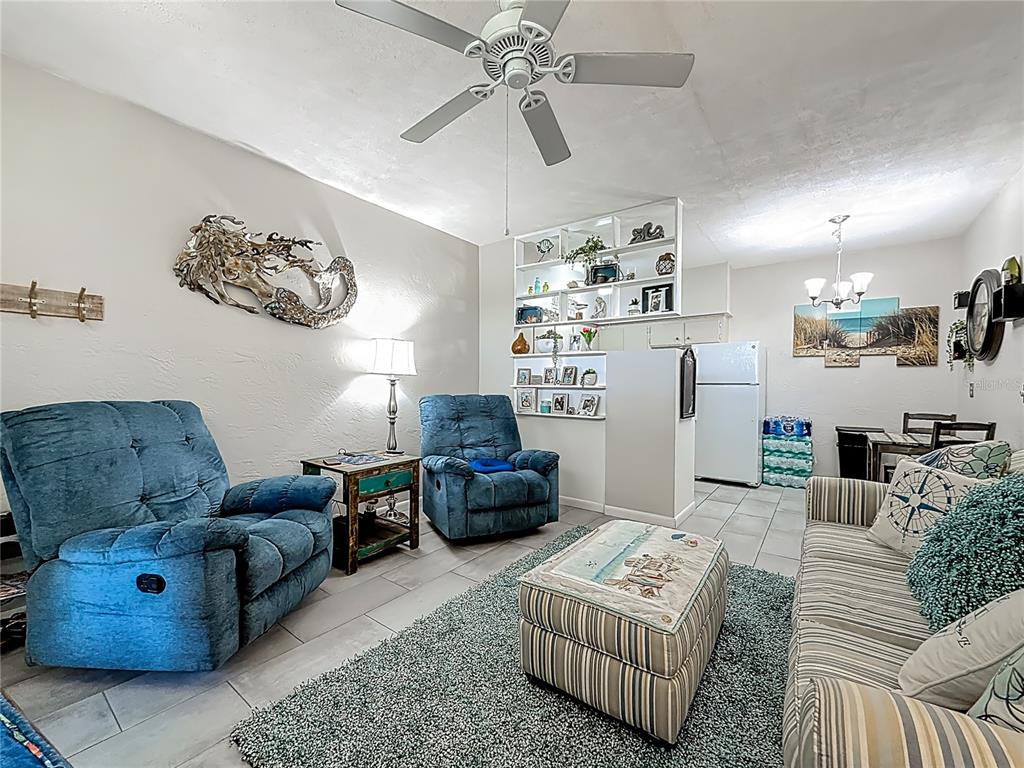 A living room features blue recliners, a striped sofa, an ottoman, and an open shelving unit — 4051 58TH STREET N UNIT 239C, ST PETERSBURG, FL