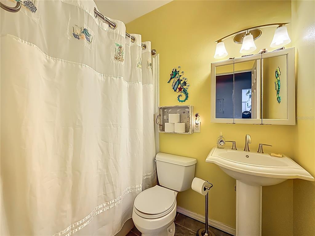 A bathroom features a pedestal sink, a toilet, a shower curtain, and yellow walls — 4051 58TH STREET N UNIT 239C, ST PETERSBURG, FL